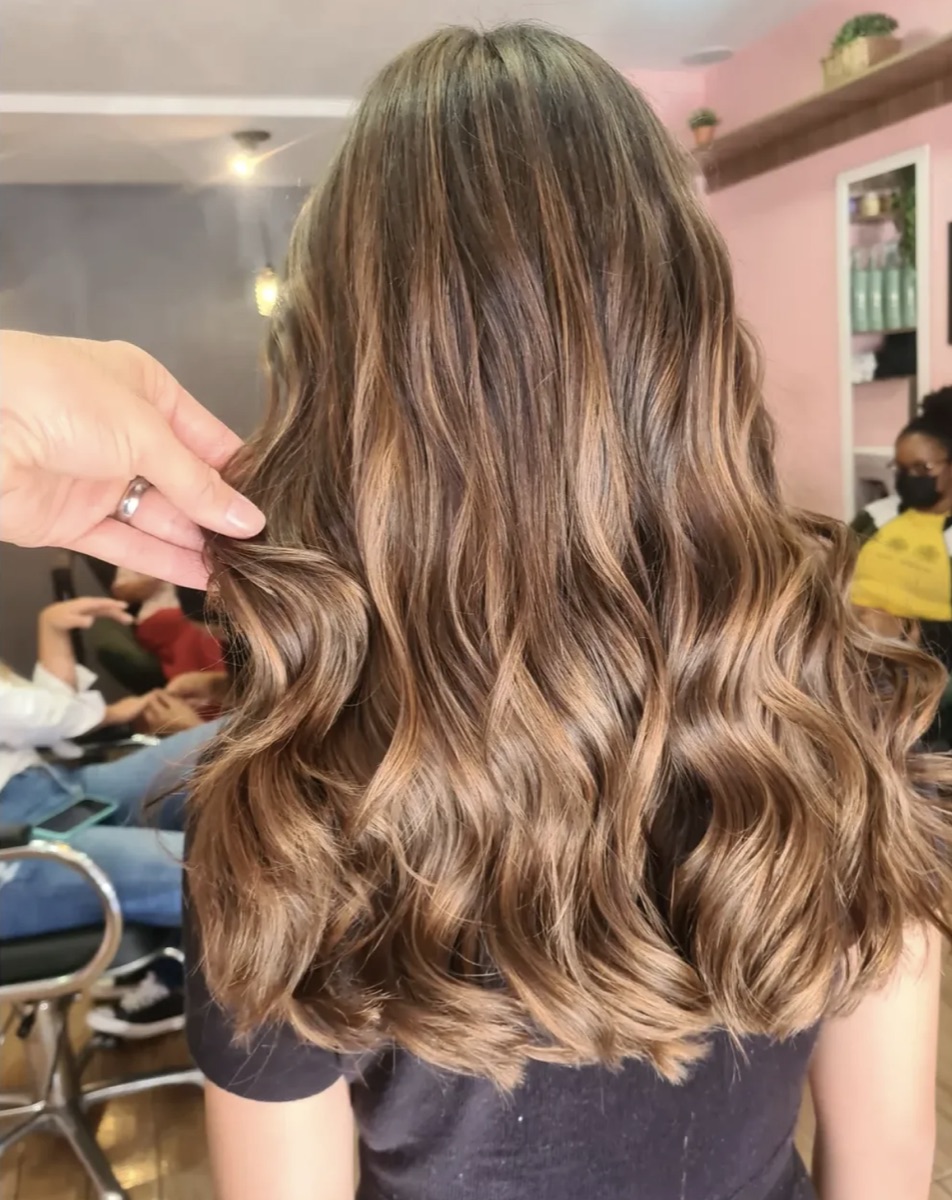 Cabelo castanho com mechas caramelo e movimento, iluminação natural