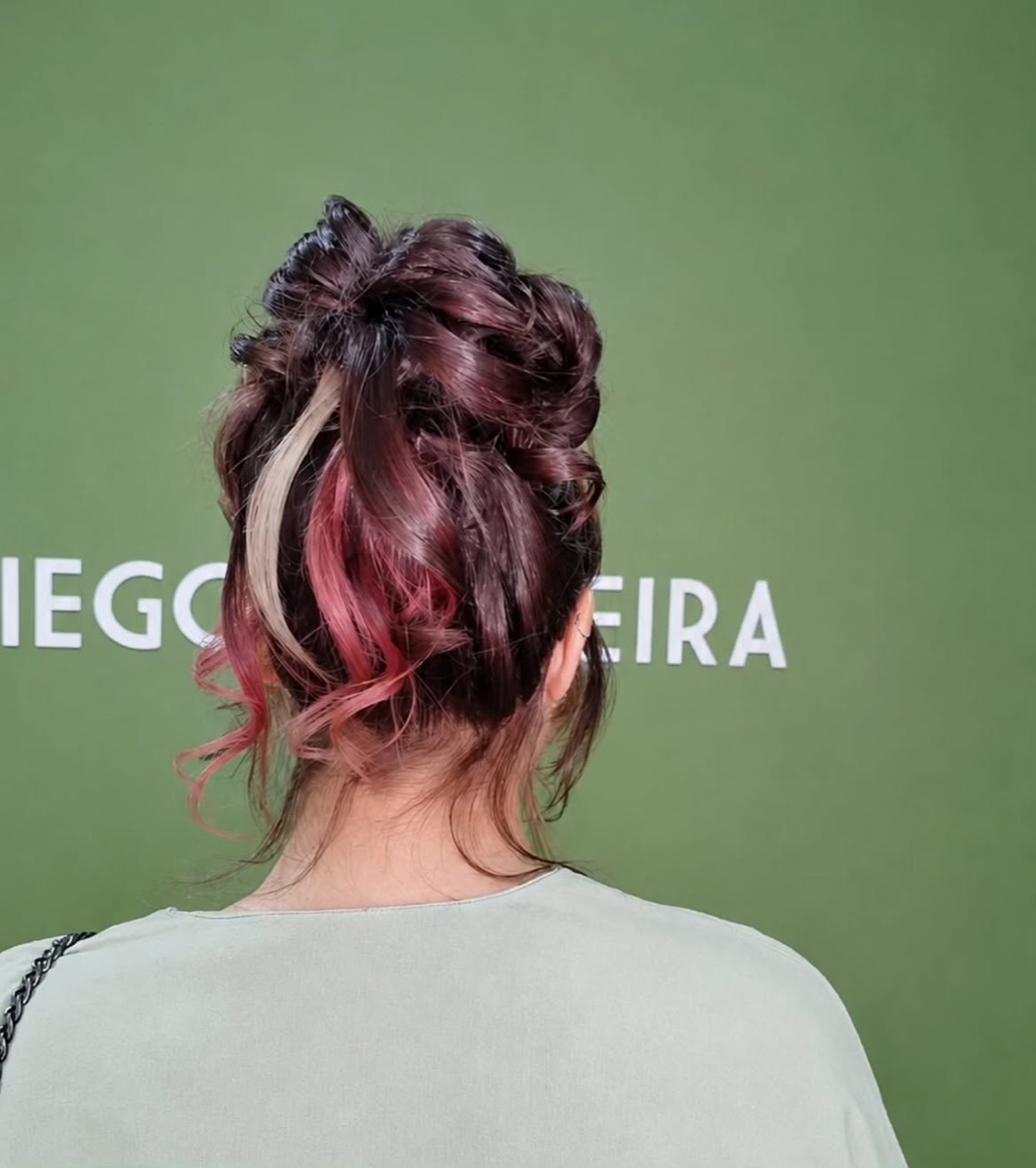 Penteado preso desconstruído com mechas coloridas vinho e rosa, vista de costas